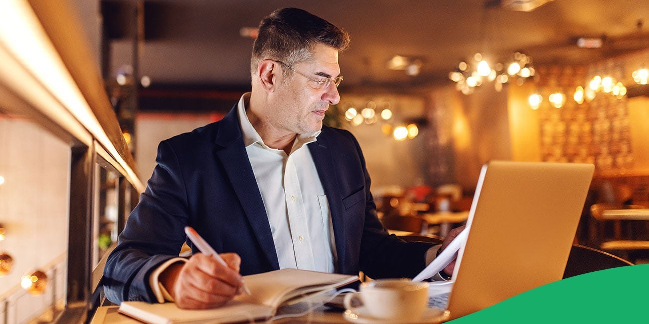 employee looking at a computer and taking notes in a notebook